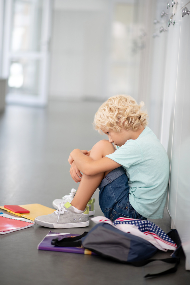 Boy sitting on floor after being bullied