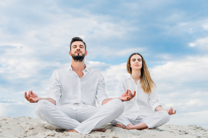 calm young couple meditating on a sandy dune