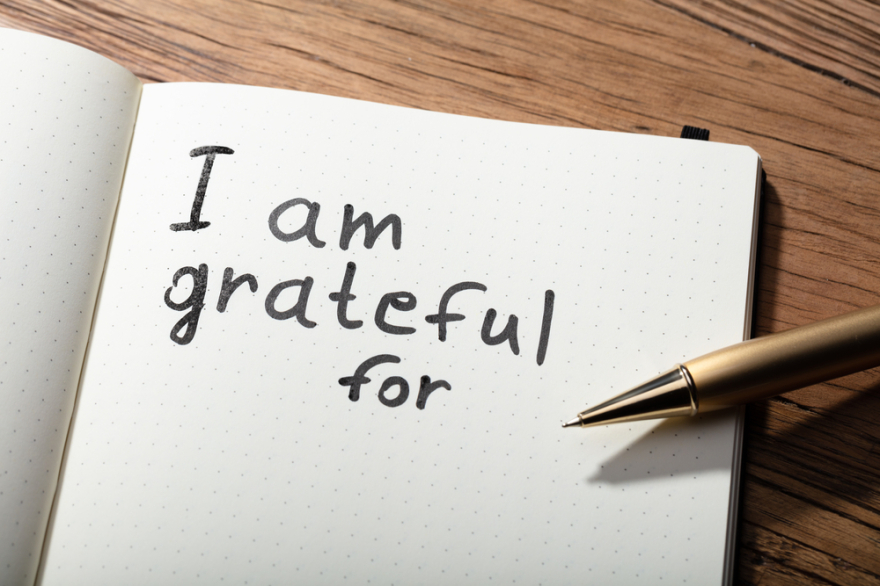 Close-up of gratitude word with pen on notebook