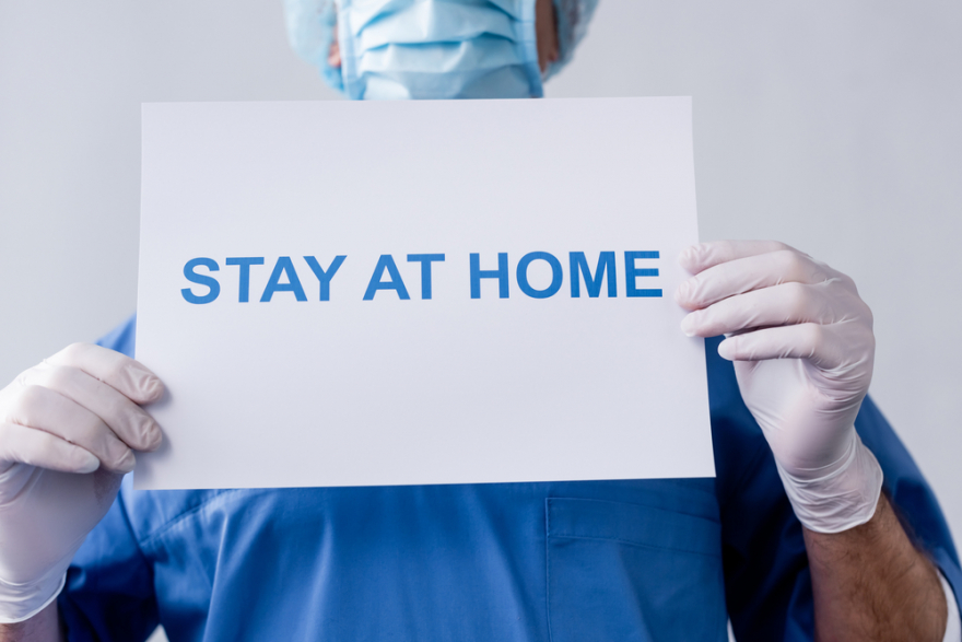 cropped view of a doctor holding a sign saying stay home