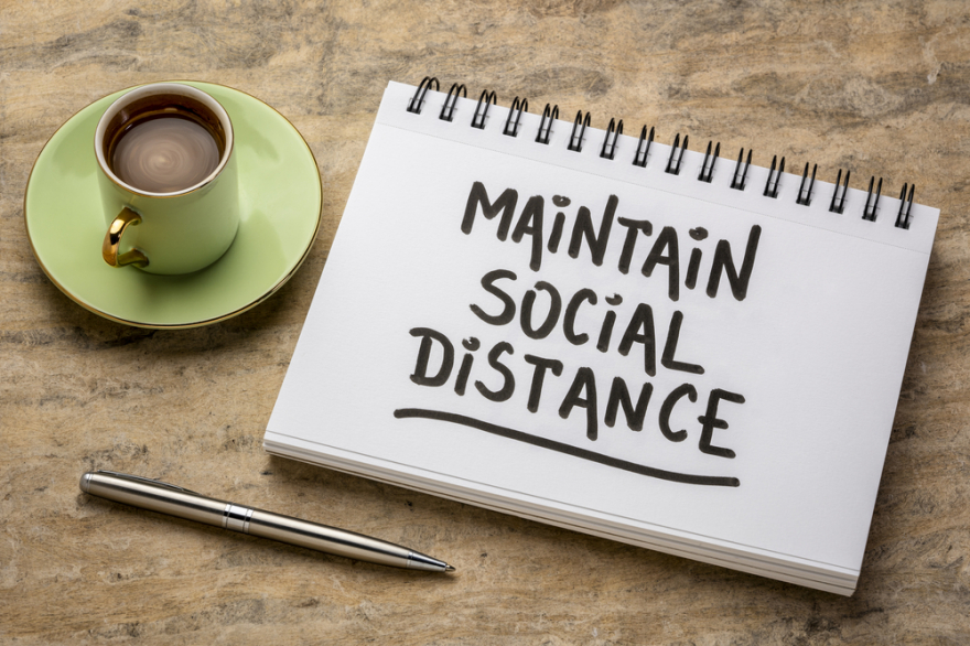 Maintain social distance written on a notepad