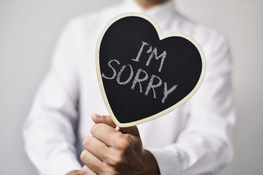 Man with a signboard saying I am sorry