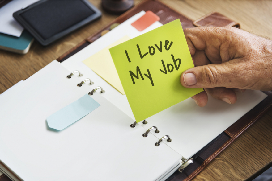 Person holding yellow sticky note with I love my job