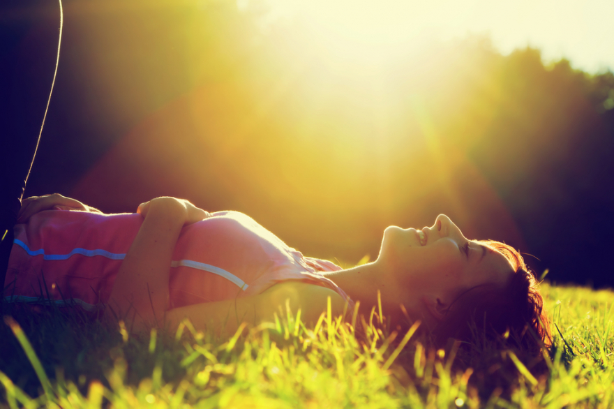 Young pretty woman lying in the grass during summer sunset